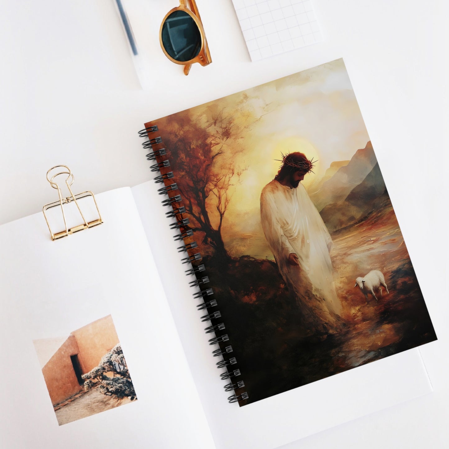 Christian spiral notebook with Jesus and lamb artwork on a white desk with office supplies