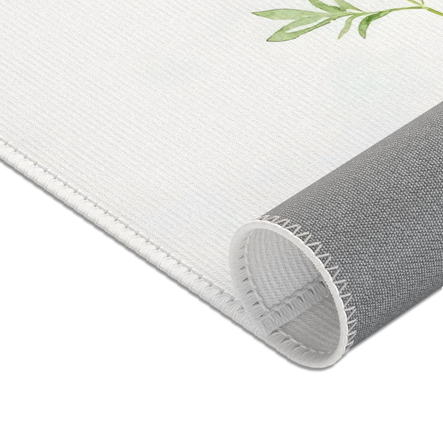 Close-up of white fabric wall art with green leaf design and stitched edge