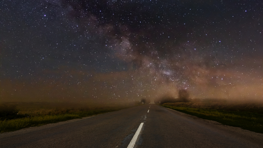 Open road at night under starry sky and Milky Way, peaceful landscape, serene atmosphere