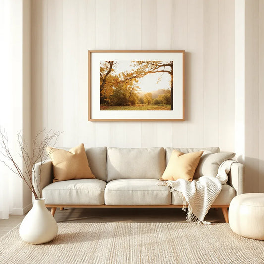 Framed fall landscape artwork with golden leaves and warm light in a cozy living room