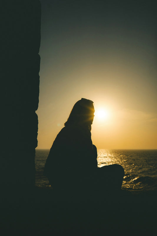Silhouette of a person watching the sunset over the ocean.