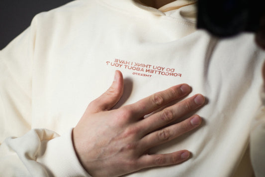 Person holding chest over cream hoodie