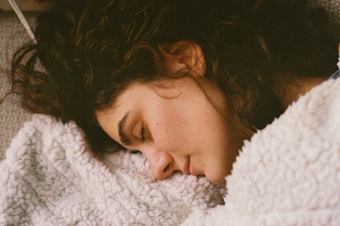 A young woman sleeping peacefully under a soft blanket