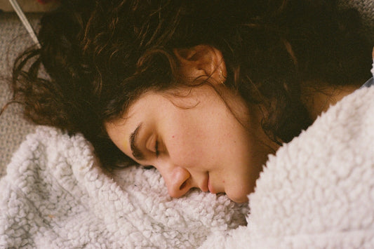 A young woman sleeping peacefully under a soft blanket