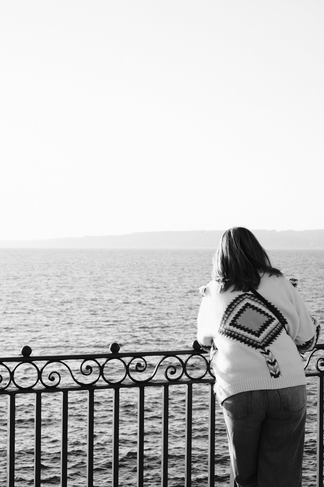 Woman in patterned sweater looking at the ocean