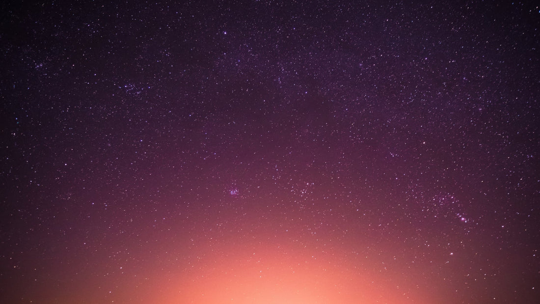 Purple night sky filled with stars above a glowing orange horizon, peaceful and contemplative.