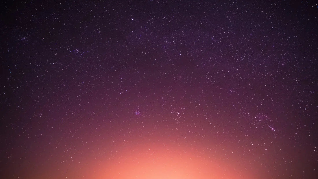 Purple night sky filled with stars above a glowing orange horizon, peaceful and contemplative.