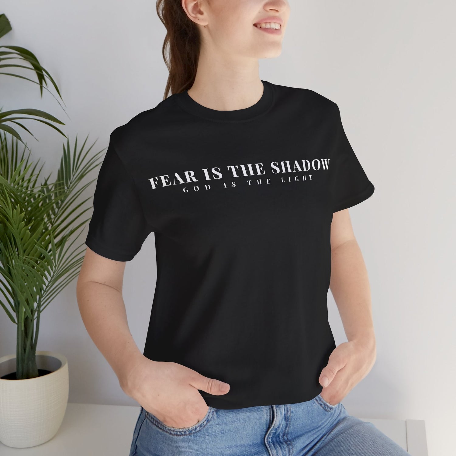 Model wearing Black Christian t-shirt with "Fear is the Shadow, God is the light" Typography.