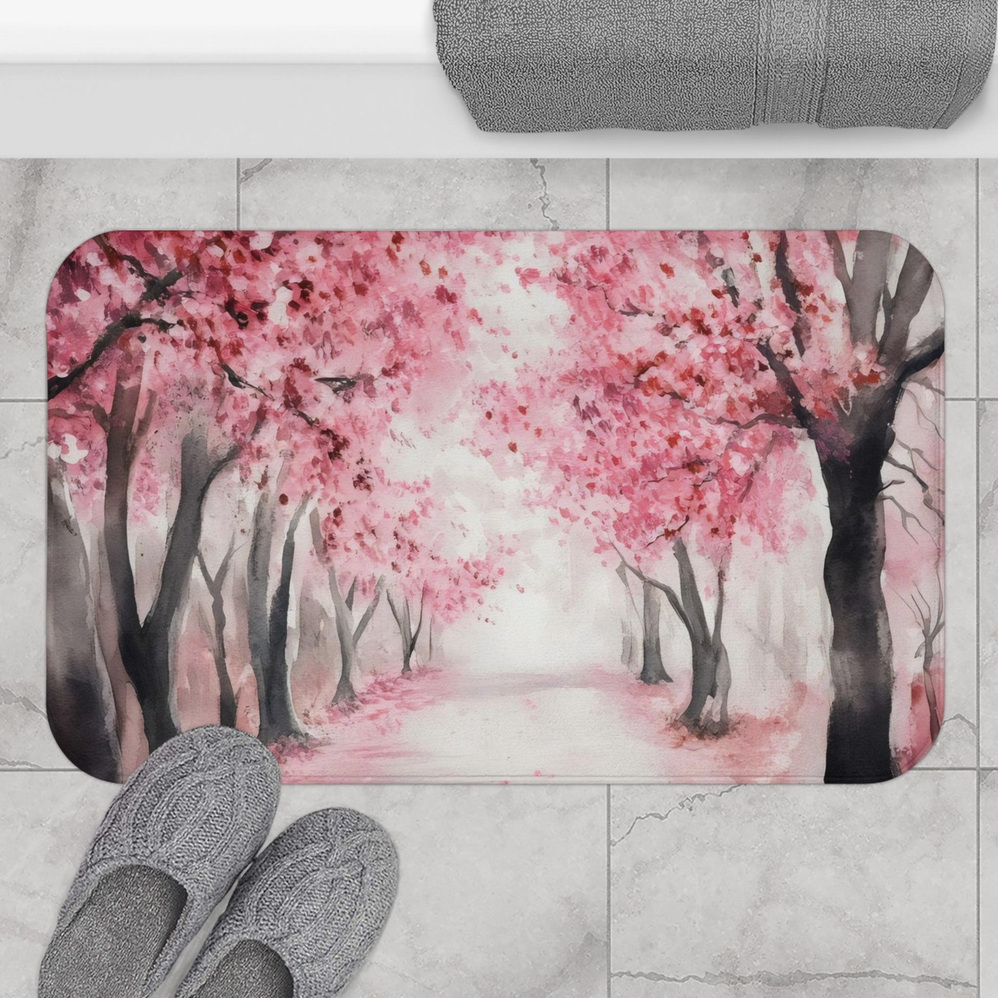 Cherry blossom bath mat with watercolor pink trees on marble bathroom floor, gray slippers visible