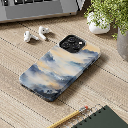 Phone case with serene watercolor mountain landscape on wooden desk, next to AirPods and laptop