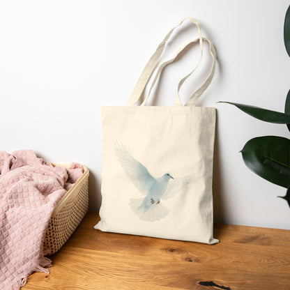Cotton tote bag with watercolor dove design, displayed on wooden table beside plant