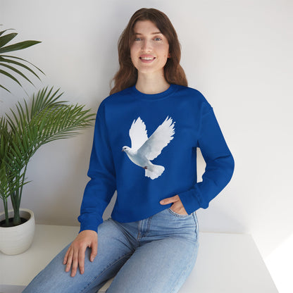 Woman in blue sweatshirt with white dove graphic, sitting by green potted plant