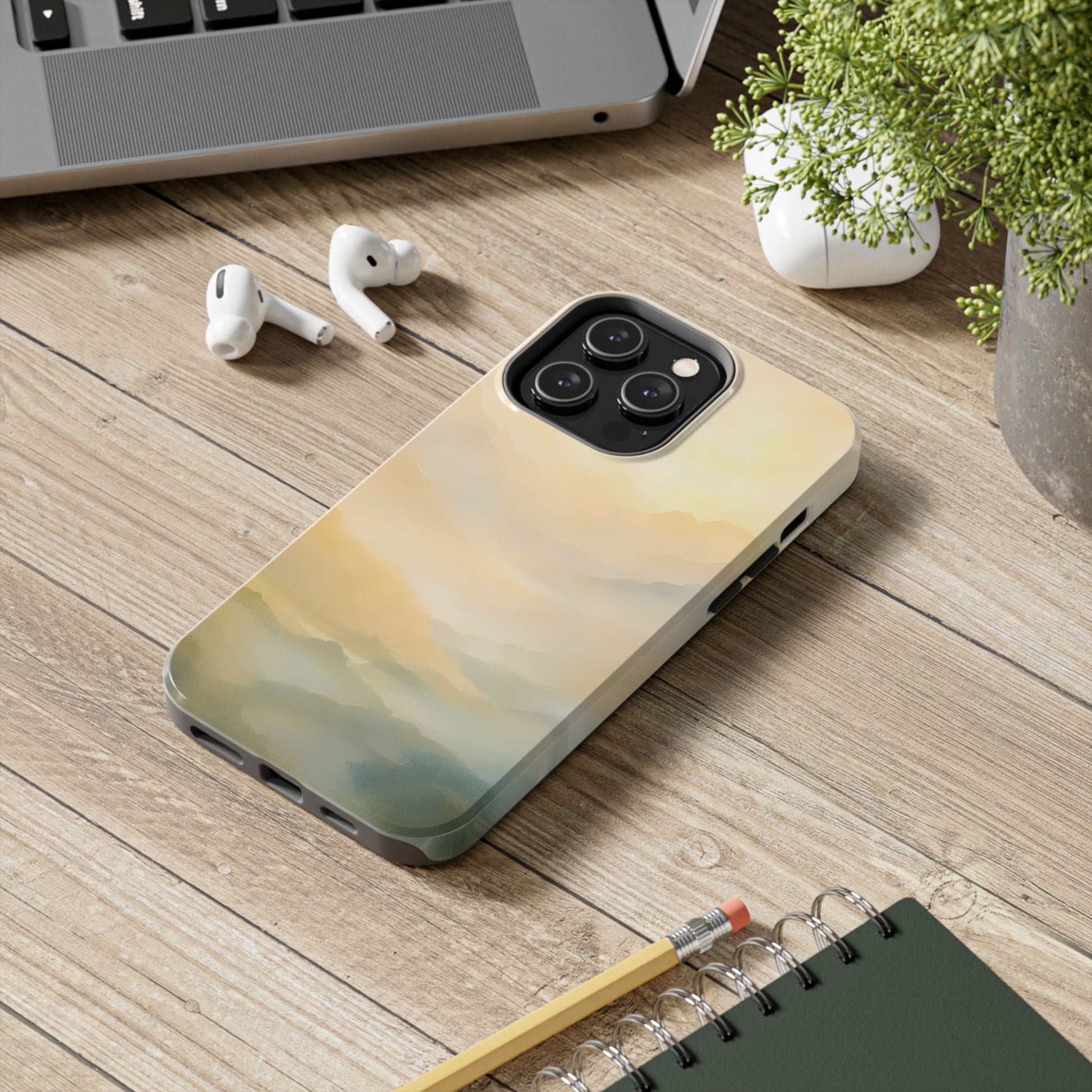 Minimalist phone case with peaceful abstract landscape design on wood desk near notebook and laptop