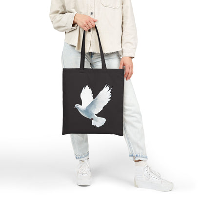 Woman holding black tote bag with white dove Christian art design, casual outfit