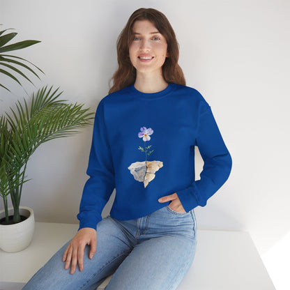 Woman in blue Christian flower graphic sweatshirt, sitting by plant, casual setting
