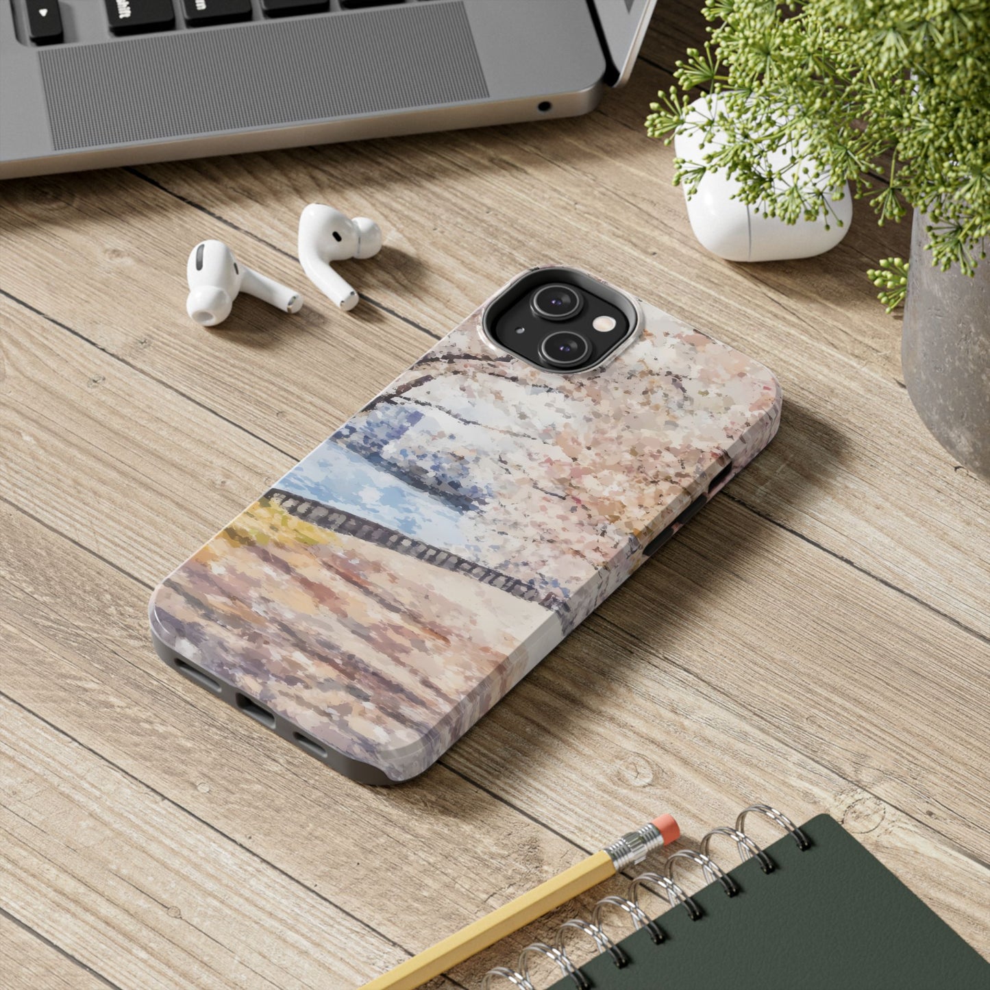Artistic Christian phone case with abstract nature scene on wooden desk beside laptop and AirPods