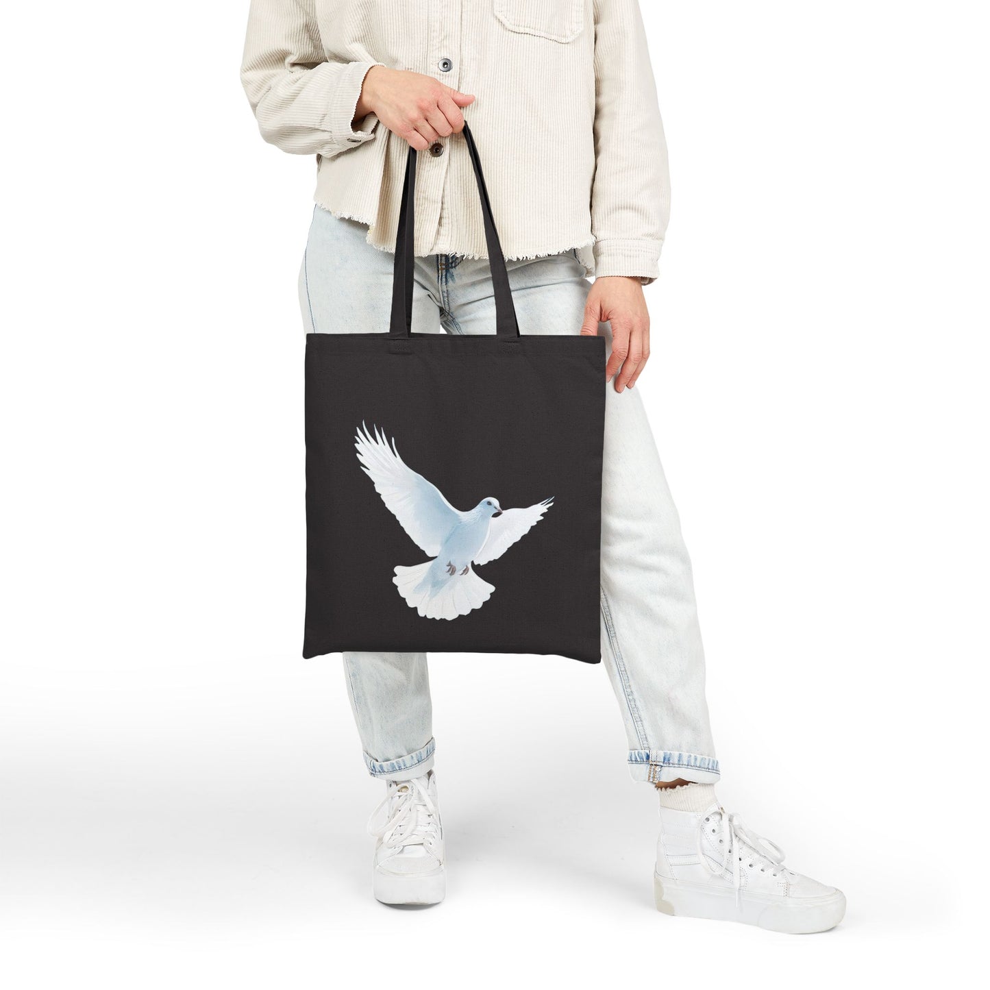 Woman holding black tote bag with white dove design, Christian faith-inspired accessory