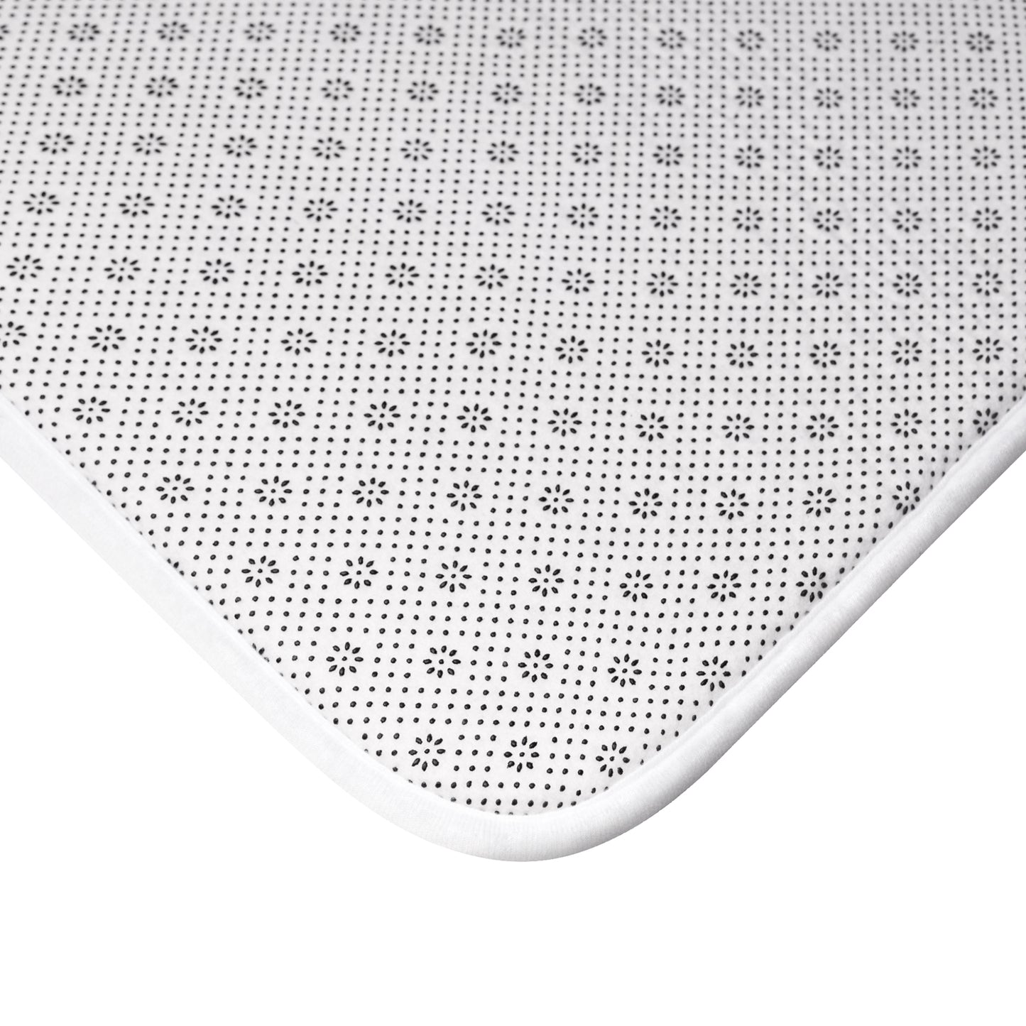 White anti-slip bath mat with black dotted floral pattern and rounded edge