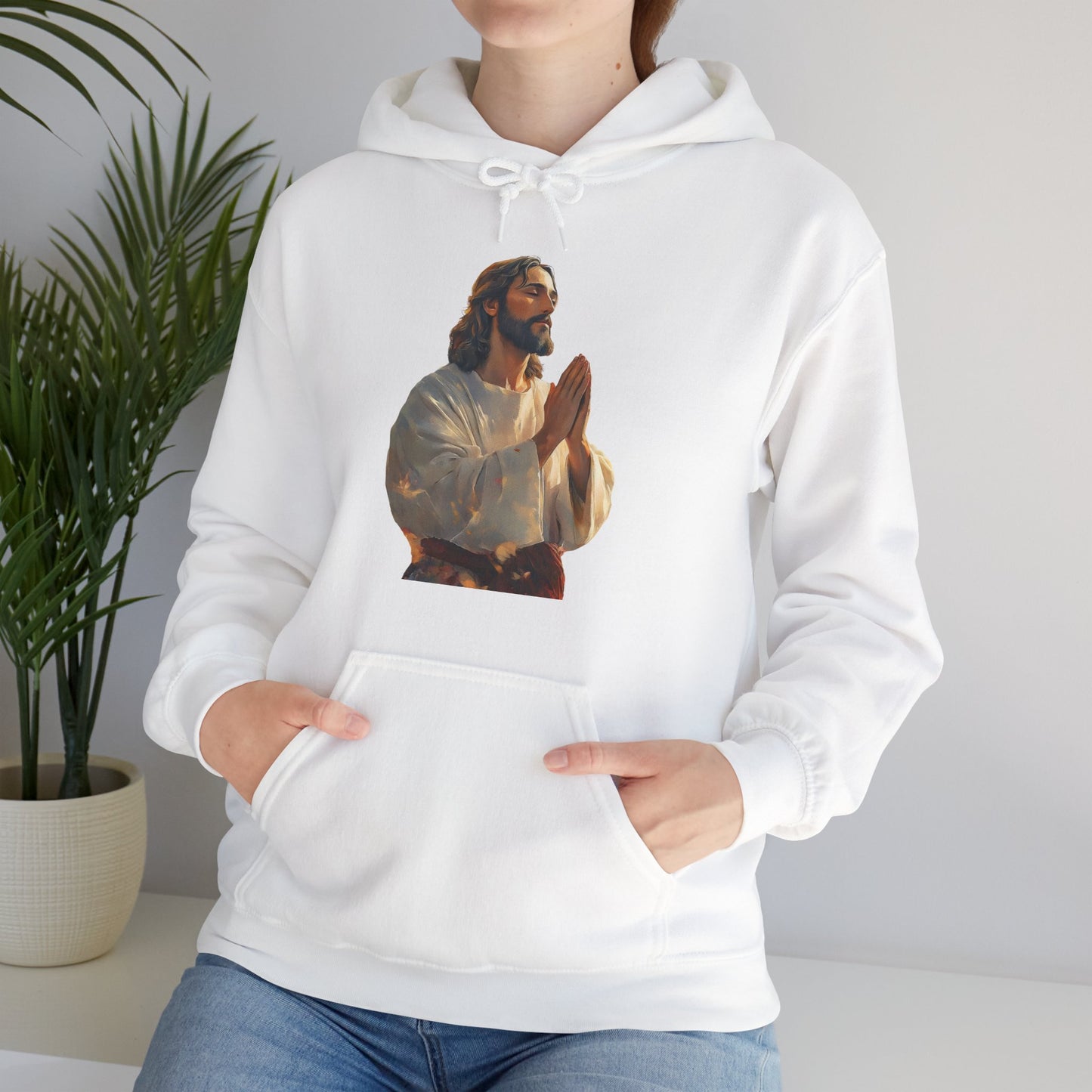 White hoodie with praying Jesus graphic, Christian apparel, worn by woman indoors with plant