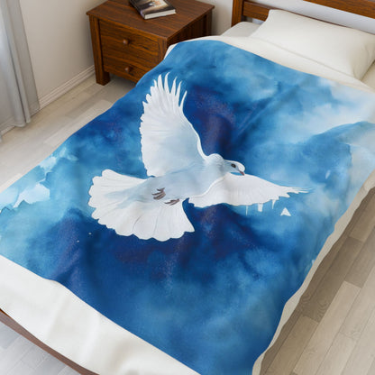 Blue and white blanket with a dove design on a bed in a bedroom.