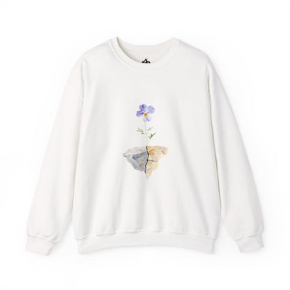 White sweatshirt featuring a purple flower growing from a cracked rock graphic, faith-inspired design