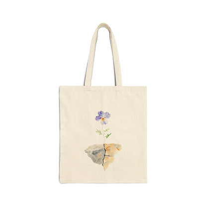Natural cotton tote bag with a purple watercolor flower growing from cracked rocks, minimalist design