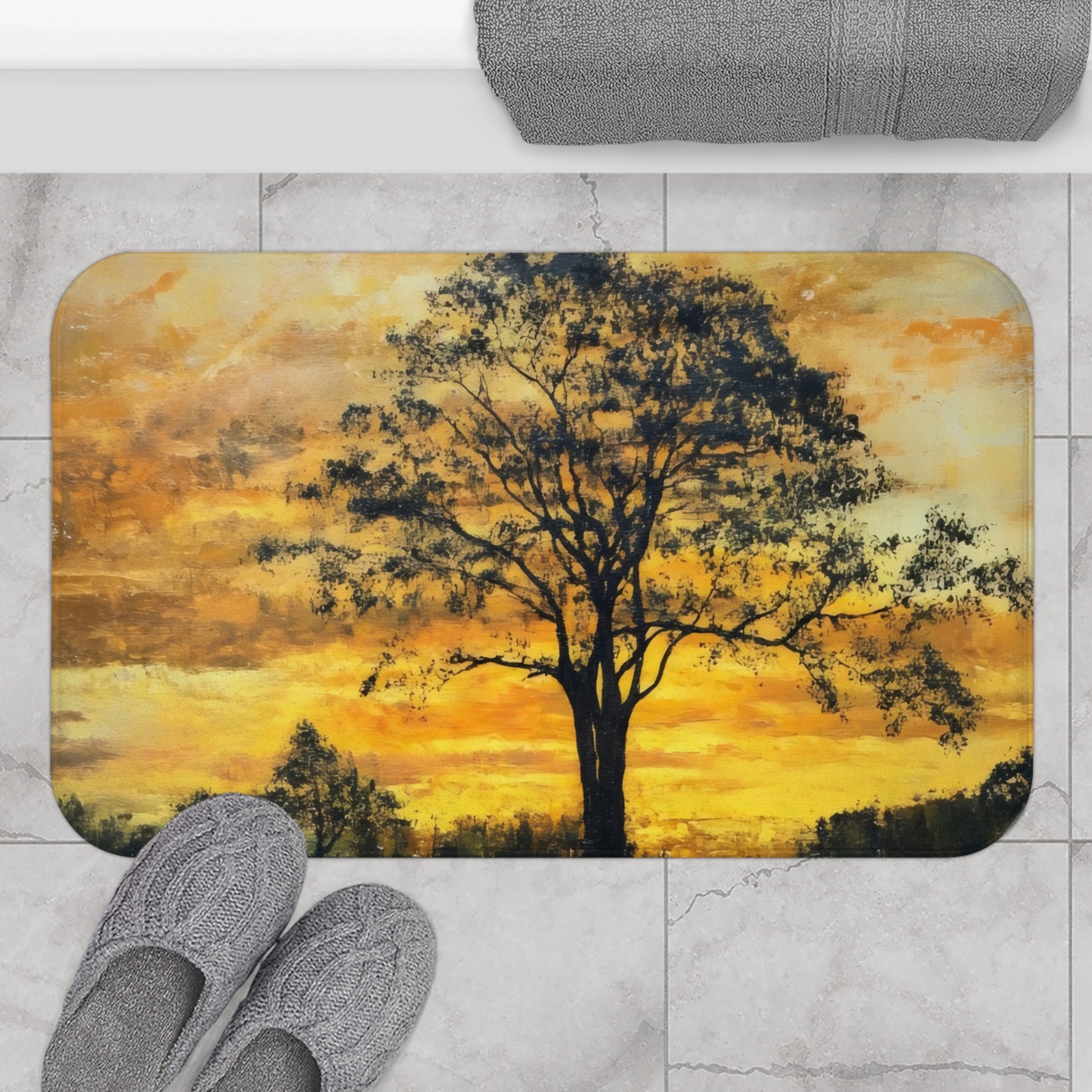 Bath mat with tranquil tree silhouette and golden sunset design, on marble floor with slippers