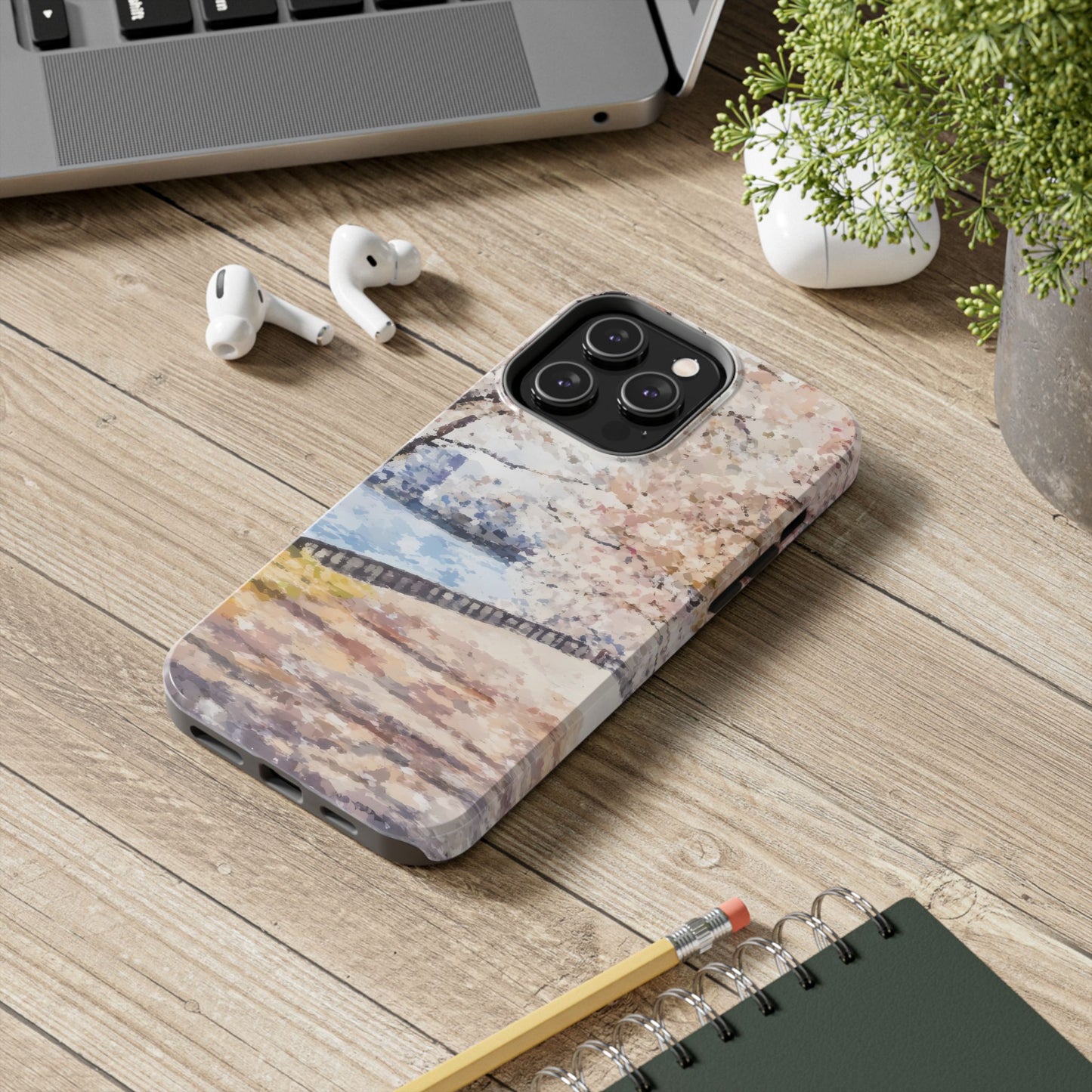 Christian art-inspired phone case with serene abstract landscape on desk beside laptop and earbuds