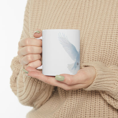 Woman holding white mug with light blue dove illustration, cozy beige sweater
