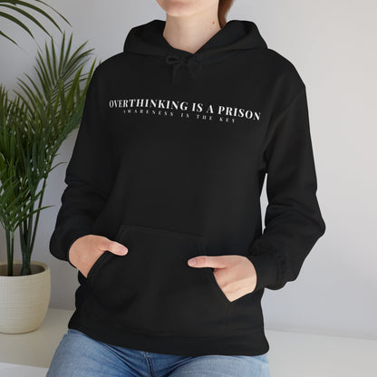Woman wearing black hoodie with 'Overthinking is a prison, awareness is the key' text, indoor setting