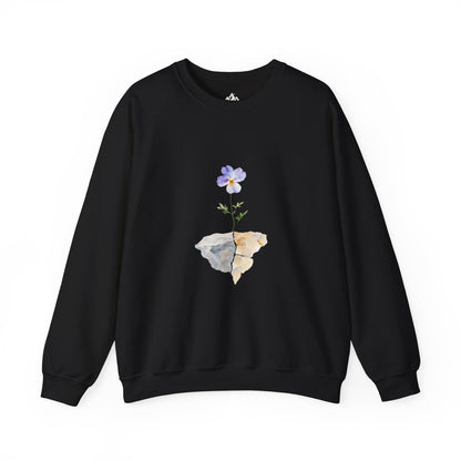 Black crewneck sweatshirt with a purple flower growing from cracked rocks, minimalist design