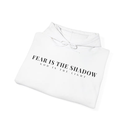 Folded white Christian hoodie with 'Fear is the Shadow, God is the Light' printed on front.
