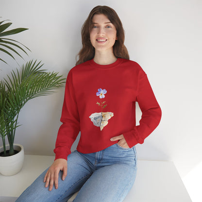 Woman in red sweatshirt with blue flower and rocks graphic, sitting next to potted plant
