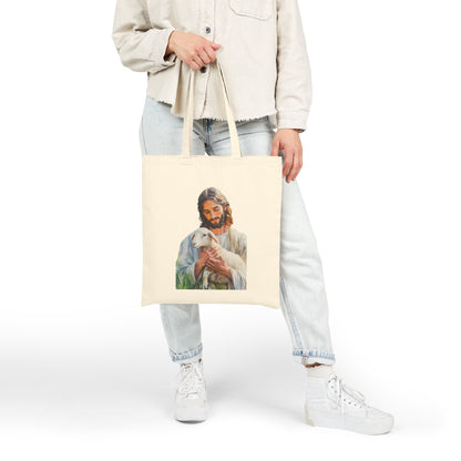 Person holding beige tote bag with Jesus holding lamb Christian art design.