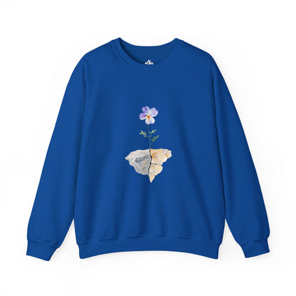 Blue sweatshirt featuring a watercolor flower growing from cracked rocks, faith-inspired apparel