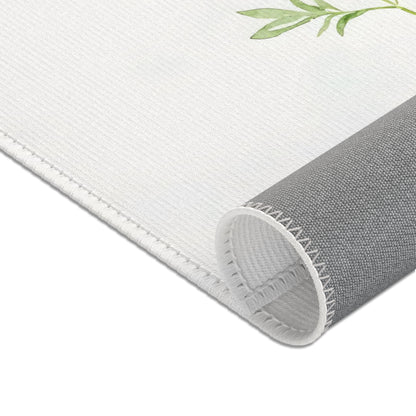 Close-up of white fabric wall art with green leaf design and stitched edge