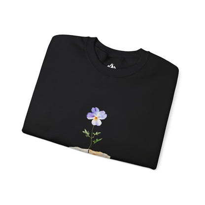 Black sweatshirt with a purple flower and green stem graphic, folded on white background