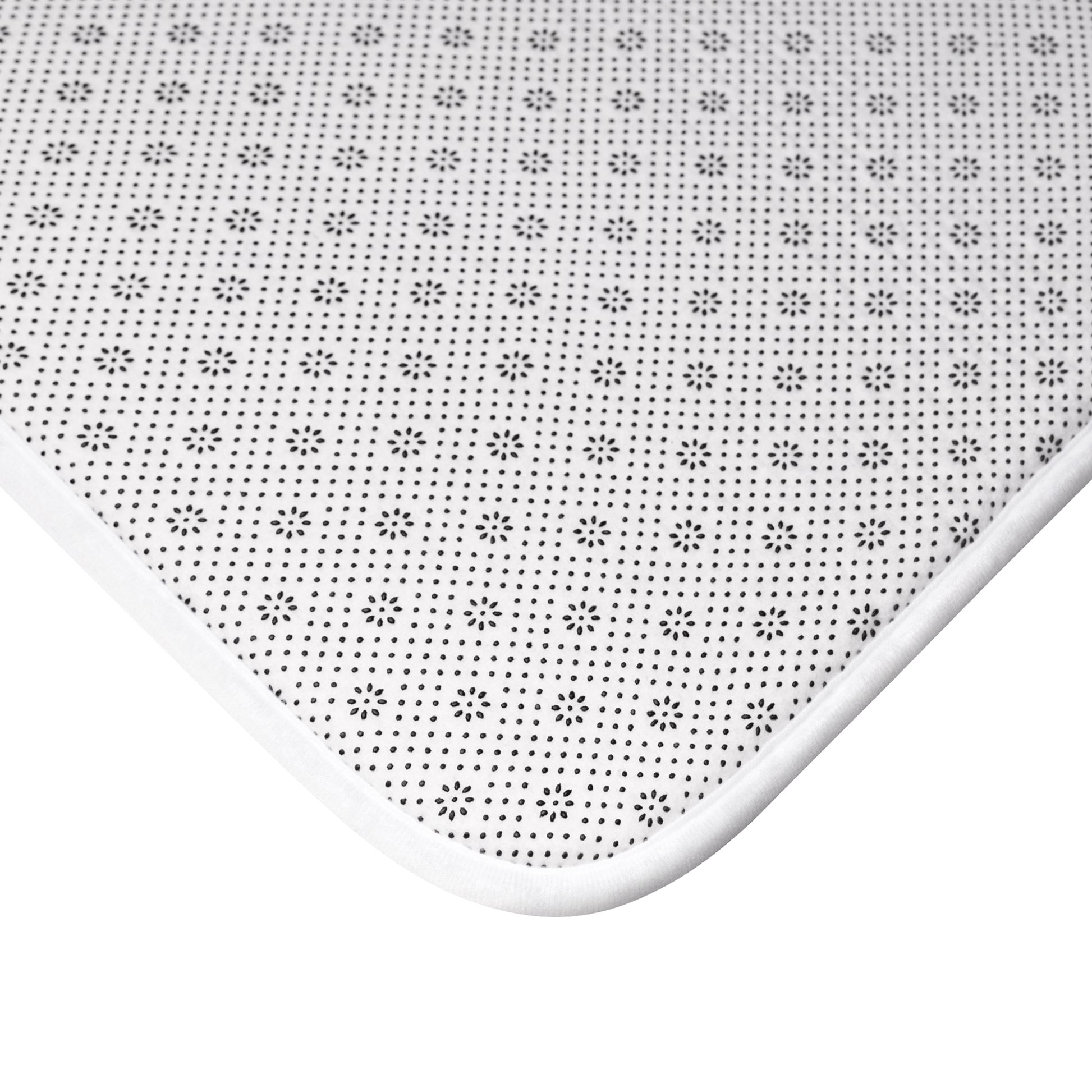 Close-up of non-slip white bath mat with black dotted and floral pattern
