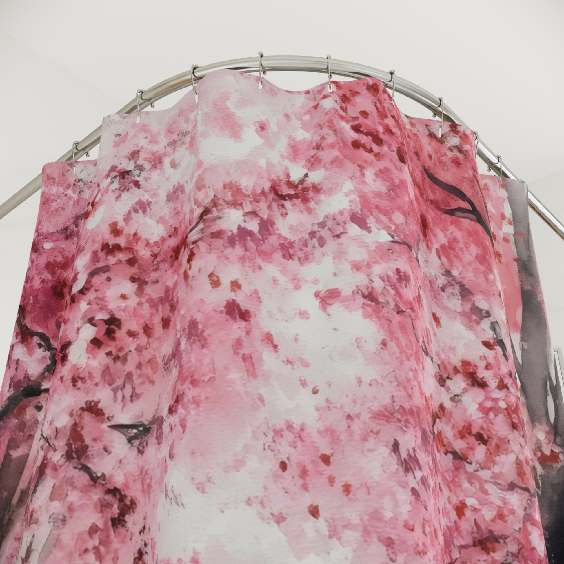 Pink cherry blossom floral shower curtain hanging on a curved rod in a bright bathroom