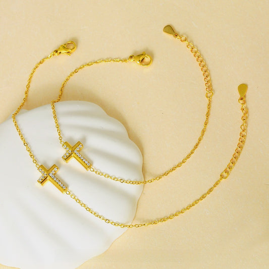 Gold-tone fine chain cross bracelets on pale display stands