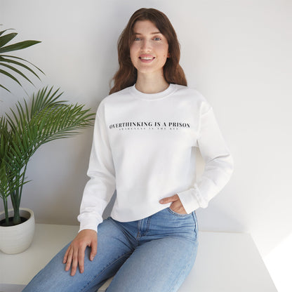 Woman in a white sweatshirt with 'Overthinking Is A Prison' text, sitting by a potted plant.