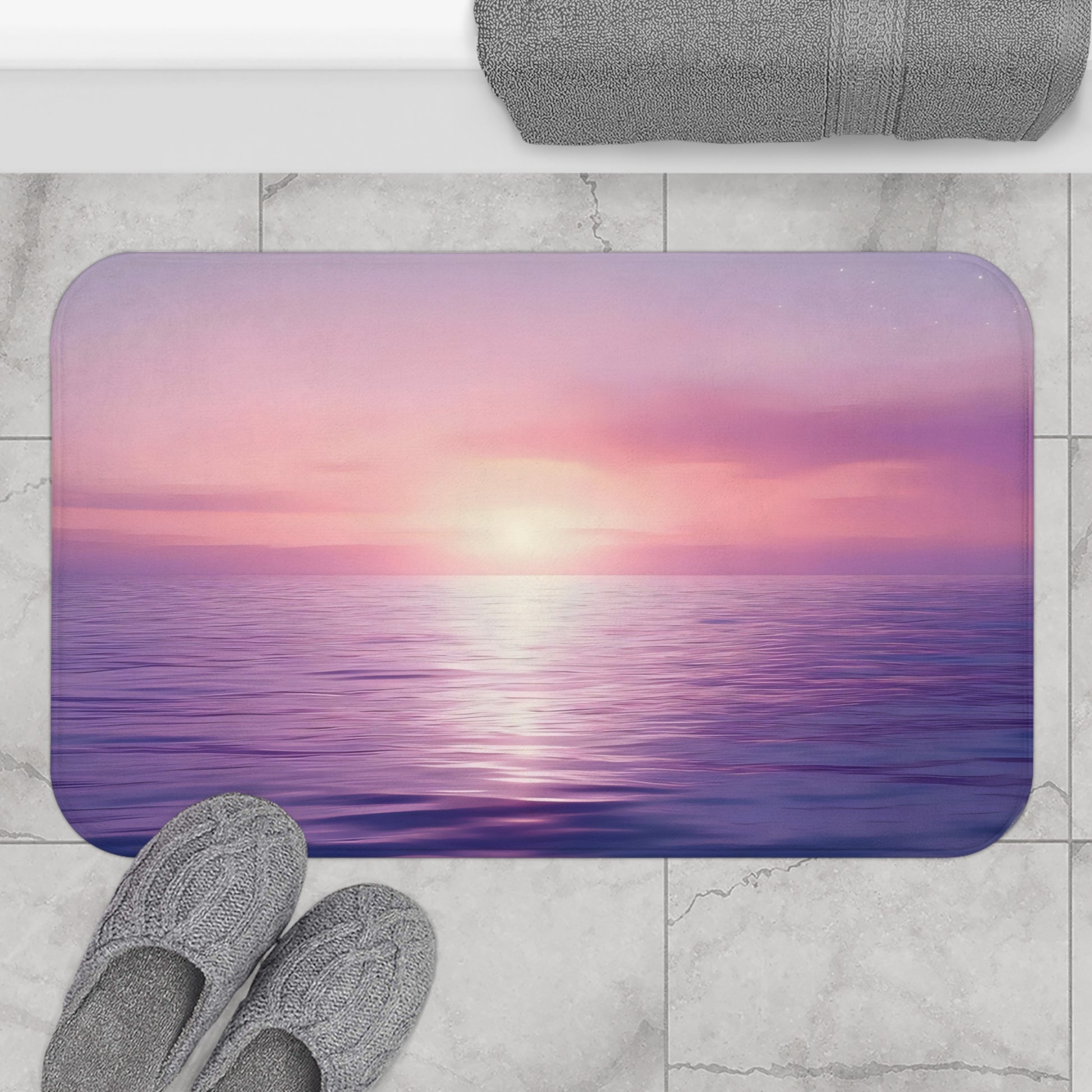 Serene ocean sunset bath mat with pink and purple sky on marble bathroom floor, cozy slippers nearby