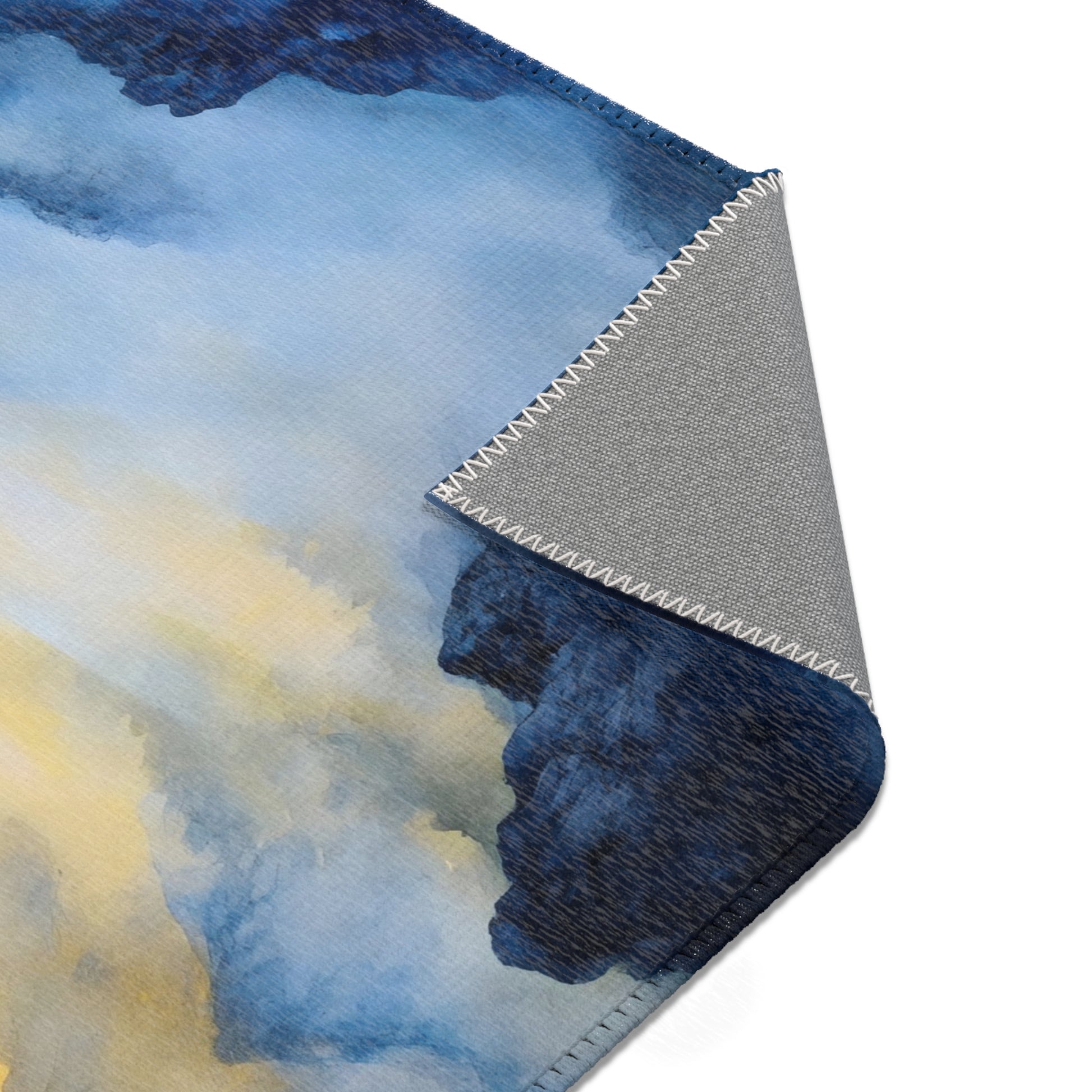 Corner of a soft blanket with blue and yellow watercolor design and visible stitching