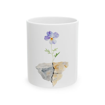 White ceramic mug with watercolor illustration of purple flower growing from cracked stone
