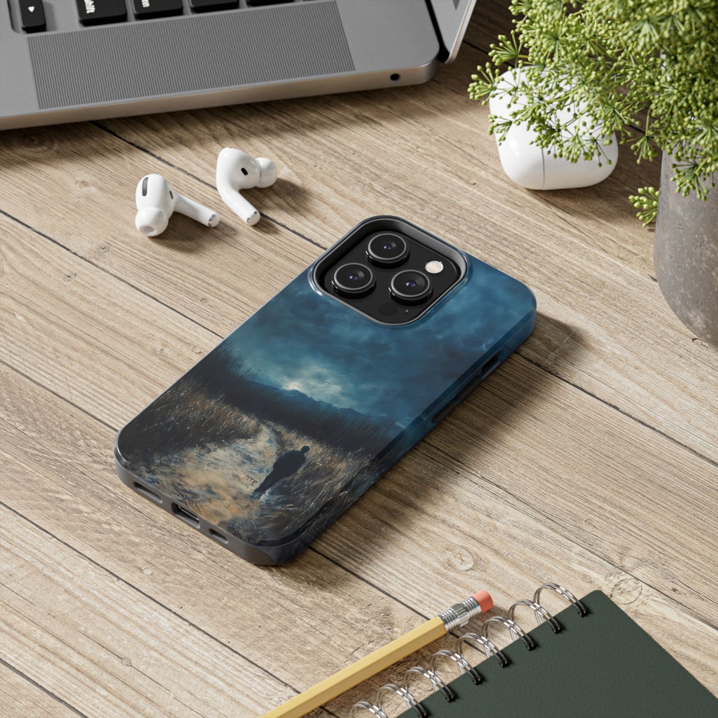 Phone case with serene landscape art of a person walking on a path at dusk on wooden desk