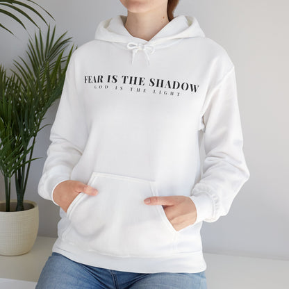Woman wearing white Christian hoodie with 'Fear is the shadow, God is the light' text.