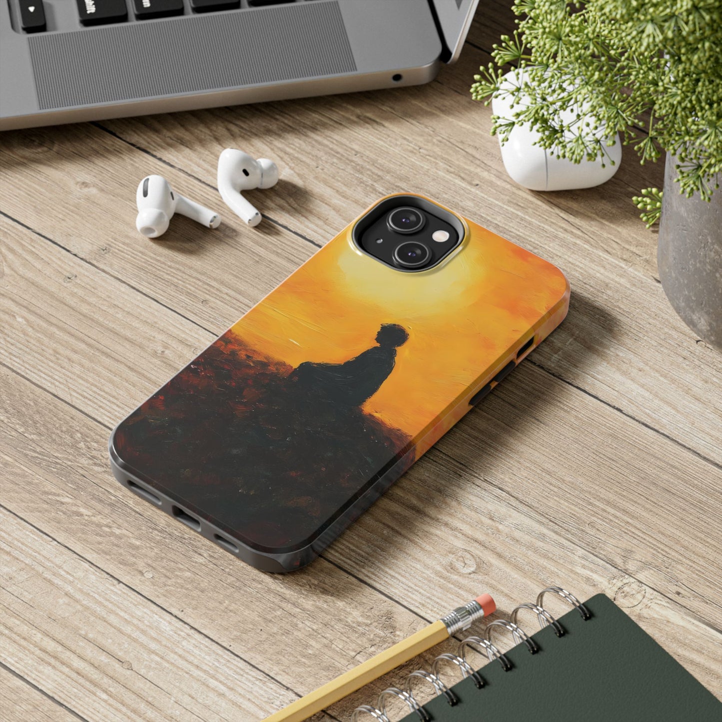 Phone case with silhouette of person meditating at sunset, spiritual art design on desk