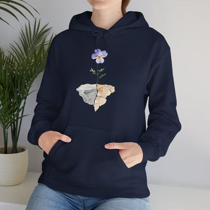 Woman wearing navy Christian hoodie with watercolor flower growing through cracked rock, casual setting