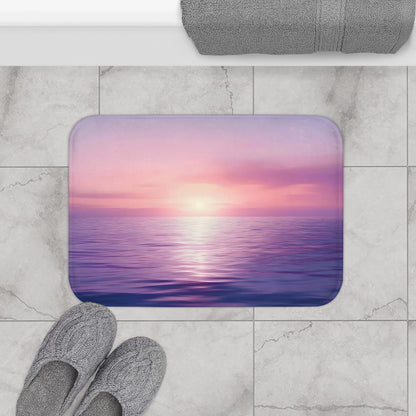 Bathroom mat with serene purple and pink ocean sunset, gray slippers, and towel on tile floor