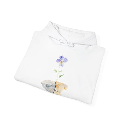 White hoodie with watercolor purple flower growing from cracked stone design, folded on white background